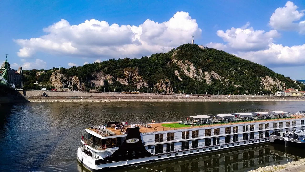 A colorful ferry in the foreground stationing on main river of Budapest. Mountain and Buda castle in the background.